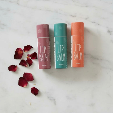 Natural herbal lip balms on a marble background with rose petals