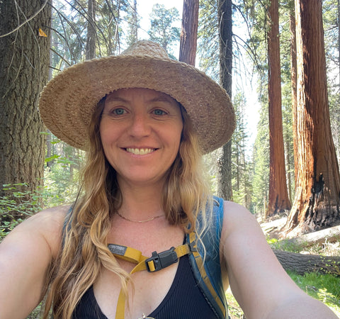 Woman taking a selfie in a forest with large trees in the background